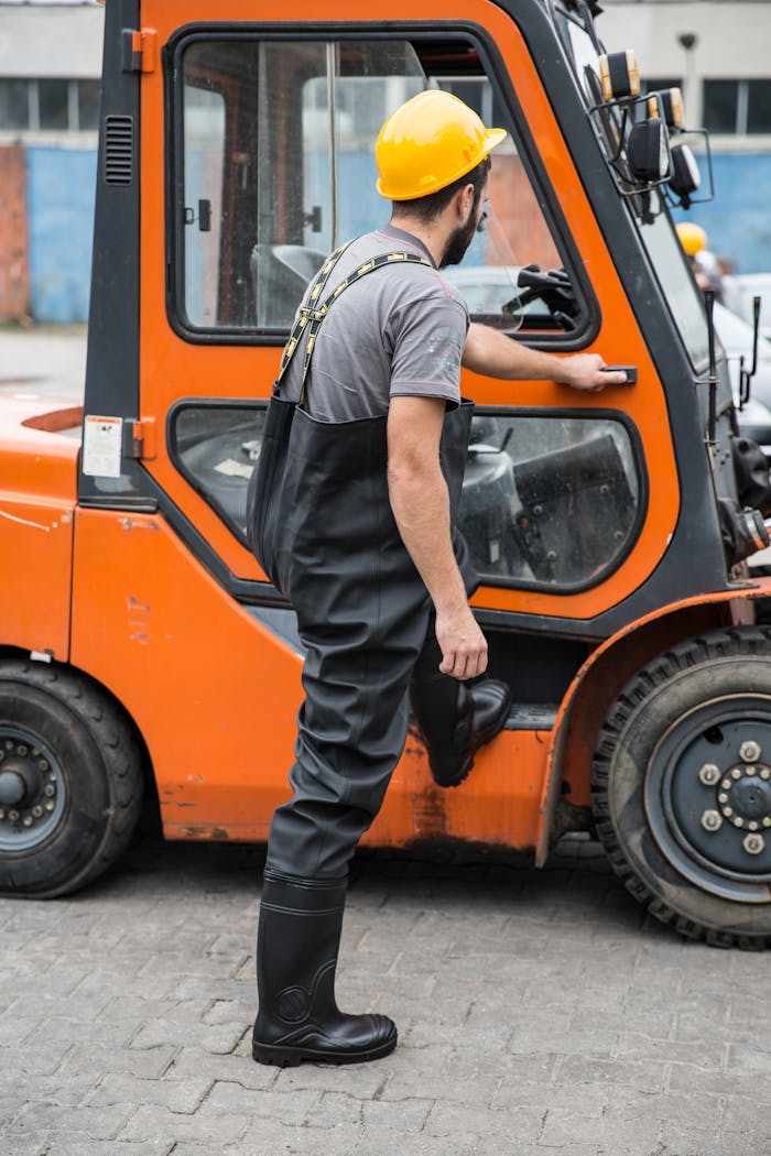 The Art of Drawing Readers In: Your attractive post title goes here Industrial worker wearing a hardhat opens a forklift door in an outdoor setting, emphasizing safety and utility.